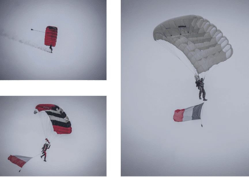 3 parachutistes sous voile avec des drapeaux et fumigènes lors d'un saut de démonstration
